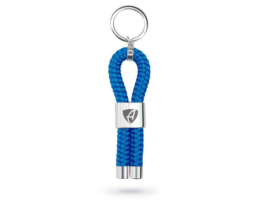Vorderansicht eines royal-blauen CB Ammersee Schlüsselanhänger mit silberner Schelle und Gravur des Ammersee Logos der Modemarke AMMERSEE BAVARIA aus Bayern, Deutschland